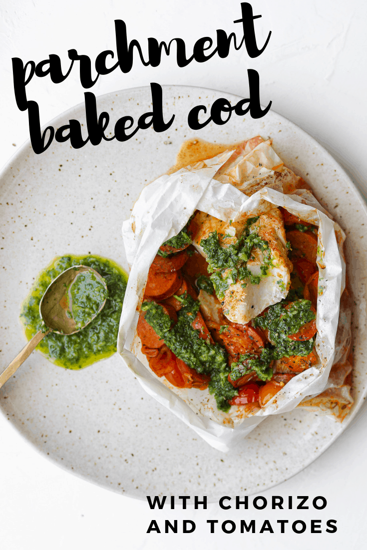 Cod in a parchment paper packet on a plate with chorizo and tomatoes