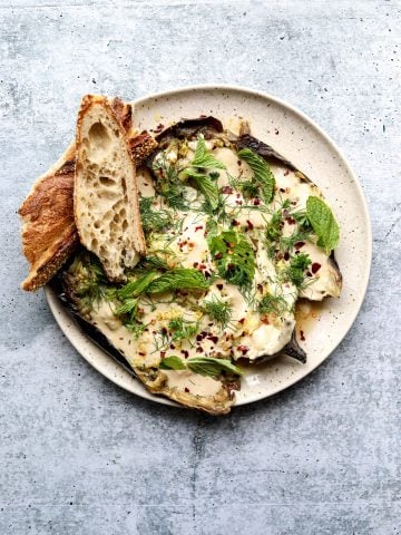 Whole Roasted Eggplant with Garlic Tahini on a plate with toasted bread