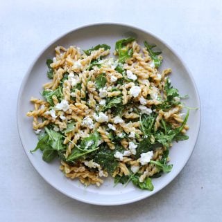 chickepea pasta with arugula and feta on a white plate