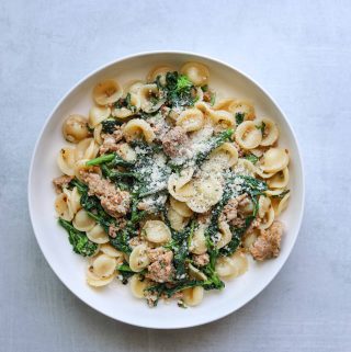 A bowl of pasta with broccoli rabe, sausage orecchiette and parmesan