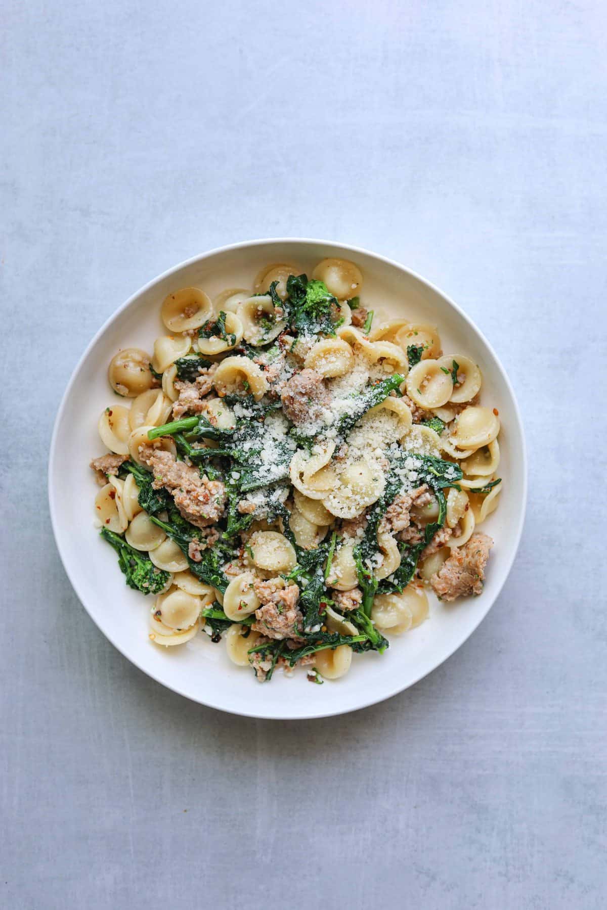 A bowl of pasta with broccoli rabe, sausage orecchiette and parmesan