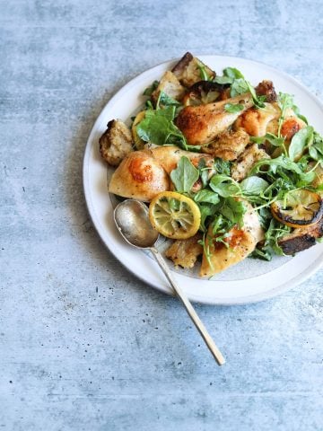 Roast Chicken with Toasted Bread Salad on a white plate with a gold spoon
