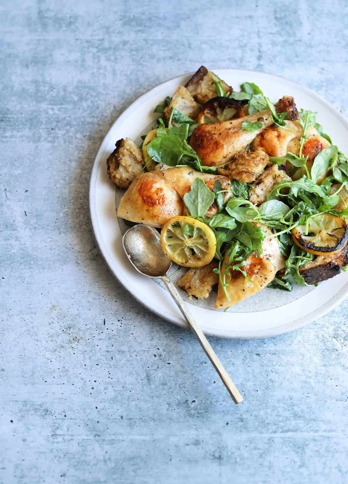 Roast Chicken with Toasted Bread Salad on a white plate with a gold spoon