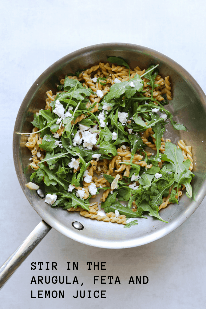 chickpea pasta in a saute pan with arugula, feta and olive oil