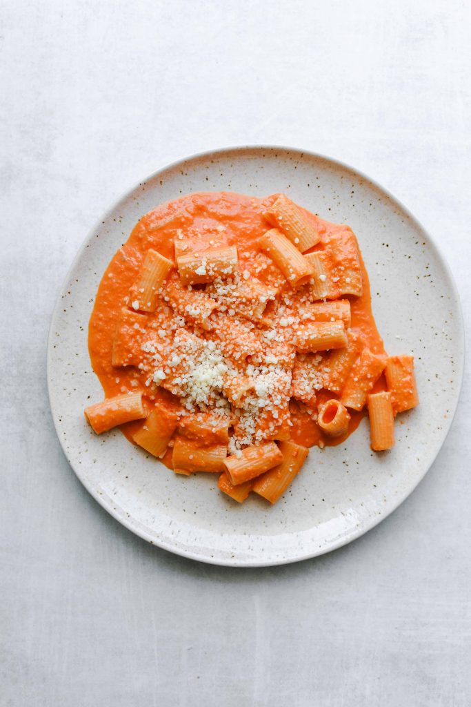 a ceramic plate with Rigatoni alla Vodka topped with parmesan cheese