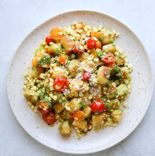 cauliflower gnocchi on with corn, tomatoes and basil on a white plate