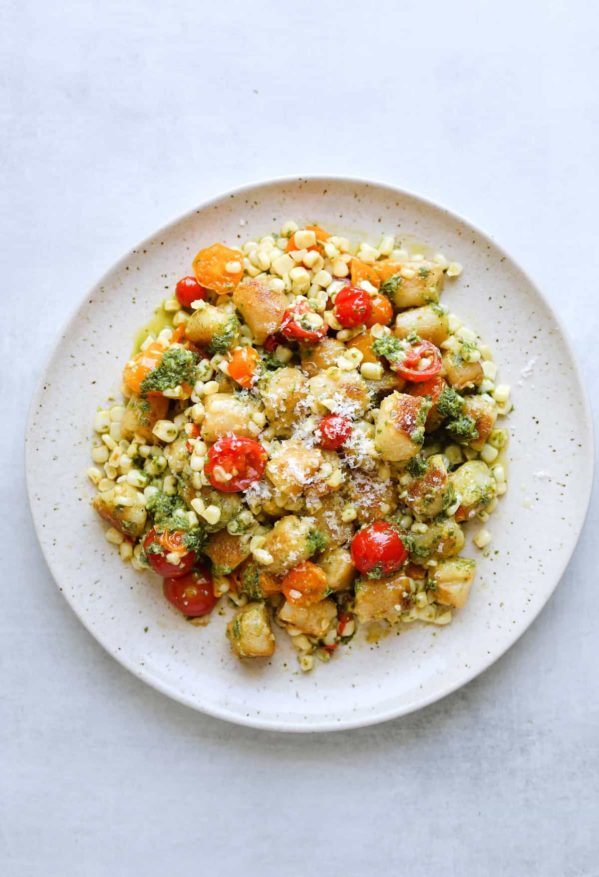 cauliflower gnocchi on with corn, tomatoes and basil on a white plate