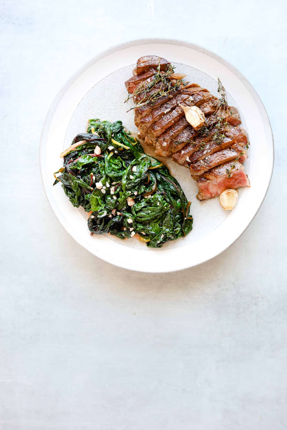 ribeye on a plate with garlicky greens