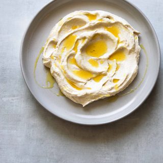 Garlicky Labneh + Tahini Dip on a plate, drizzled with olive oil