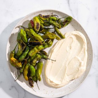 blistered shishito peppers on a plate with soy-garlic mayo