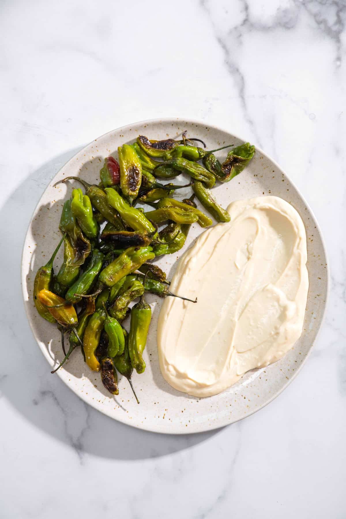 blistered shishito peppers on a plate with soy-garlic mayo