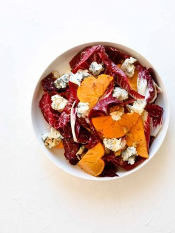 Persimmon and Blue Cheese Salad with Grainy Mustard Vinaigrette in a bowl
