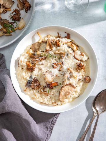 Creamy Roasted Mushroom Risotto with Truffle Oil In a bowl with a blue background