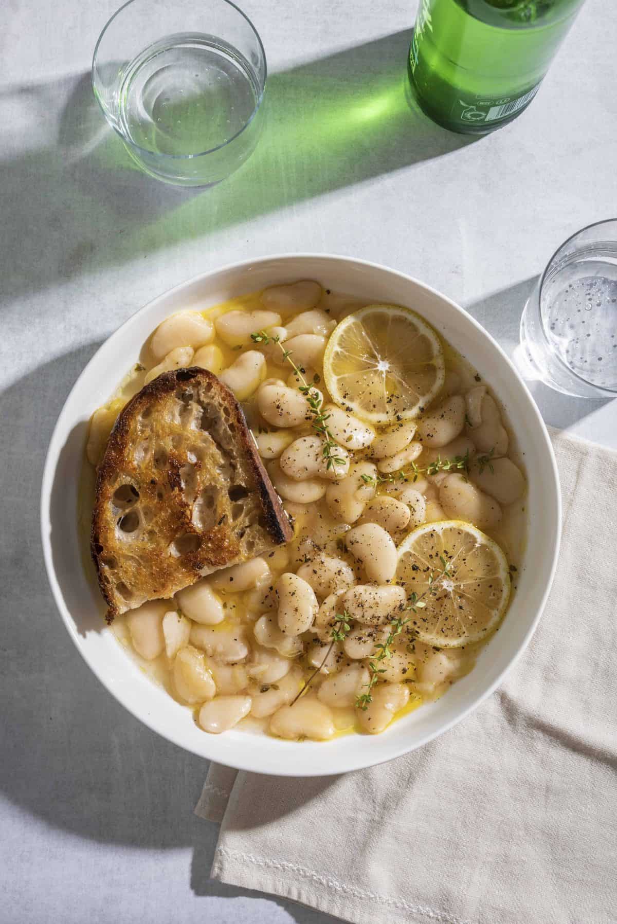 Brothy White Beans with Parmesan + Lemon in a white bowl