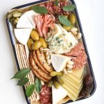A charcuterie and cheese platter on a rectangular tray