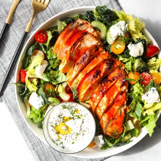 a bowl of buffalo chicken salad on a blue linen with a fork and knife on the side