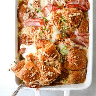 Croque Monsieur Croissant Bake in a white baking dish with a silver spoon