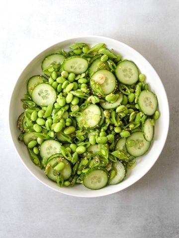 Edamame salad in a white bowl on a blue background.
