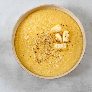 a bowl of parmesan polenta with butter, and cracked black pepper