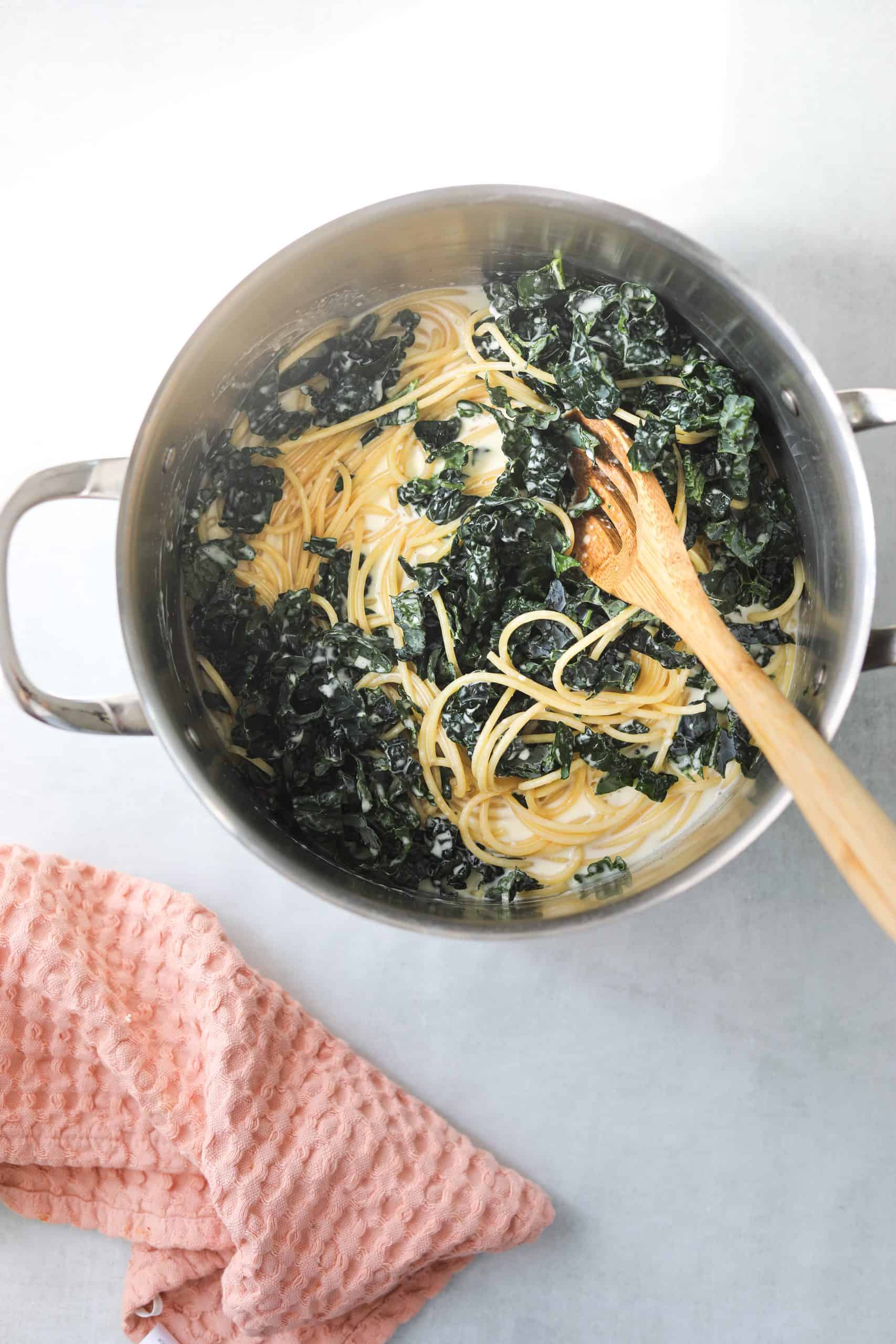 a large pot with bucatini, kale and creamy lemon sauce