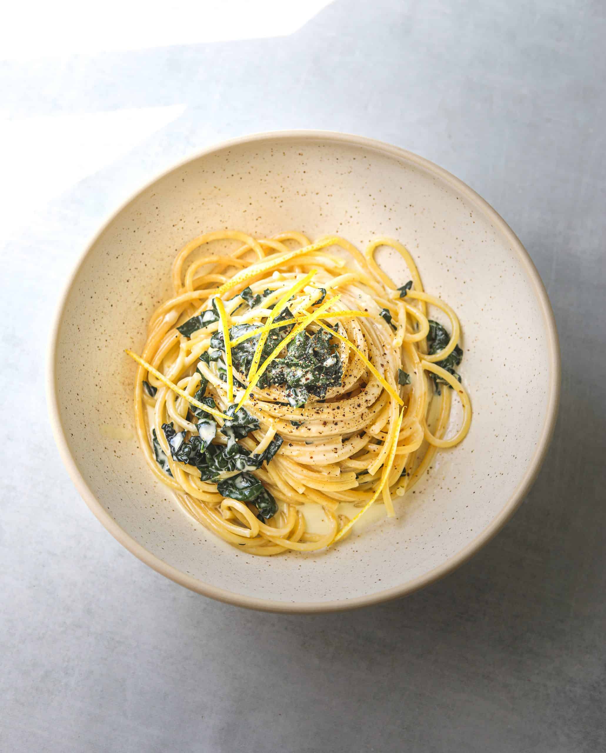 a white bowl filled with Bucatini al Limone with Wilted Kale