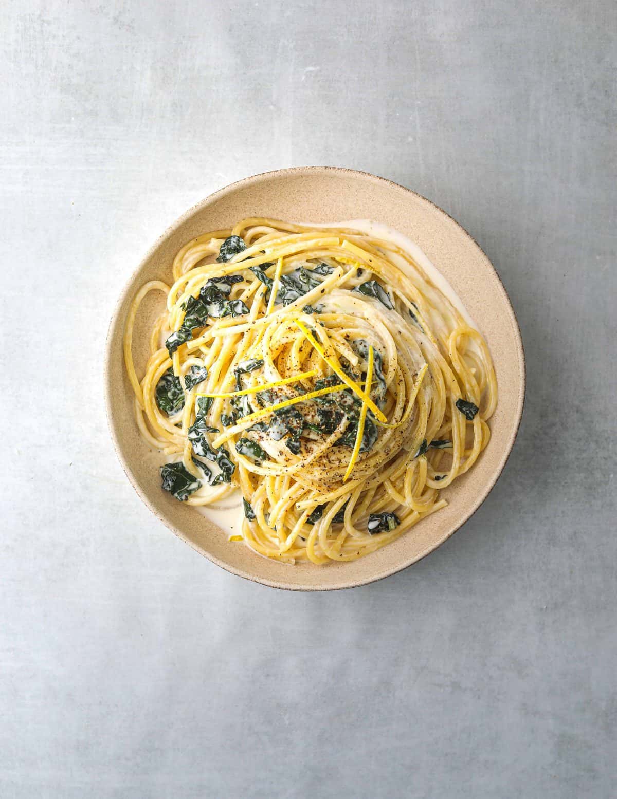 a white bowl filled with Bucatini al Limone with Wilted Kale