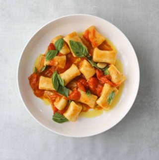 Ricotta Gnocchi with Quick Cherry Tomato Confit in a white bowl on a blue background