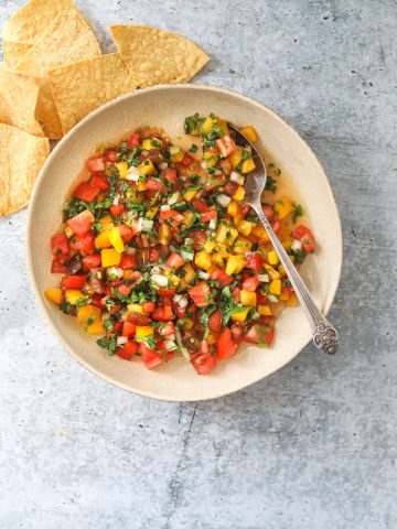A bowl of fresh heirloom tomato pico de gallo salsa with tortilla chips on the side