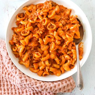 a white bowl of Creamy Calabrian Chili Bolognese with a pink tea towel