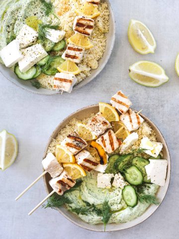 two bowls of Grilled Swordfish Kebabs with Green Goddess Yogurt with couscous, feta cheese and cucumber