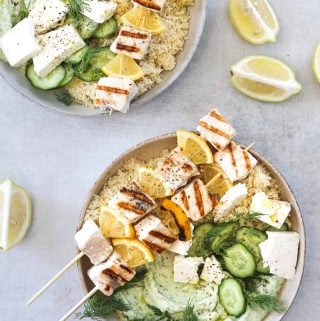 two bowls of Grilled Swordfish Kebabs with Green Goddess Yogurt with couscous, feta cheese and cucumber