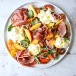 a white plate filled with Burrata Salad with Prosciutto and Nectarines