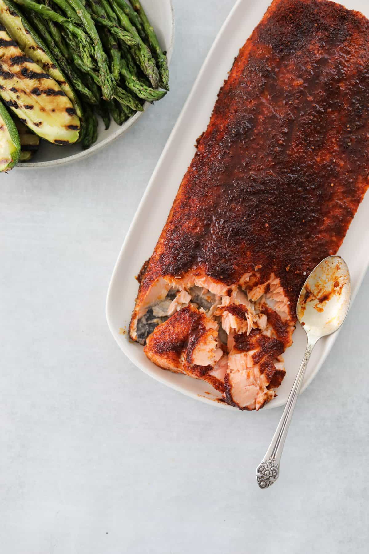 An oval platter with Oven Roasted BBQ Salmon and a side of grilled veggies