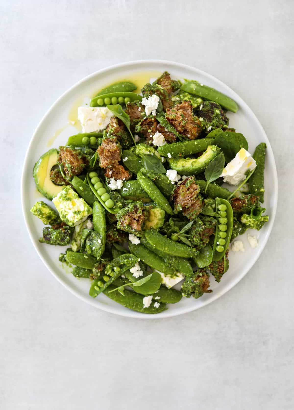 a white plate filled with Avocado Panzanella with Snap Peas + Feta Cheese