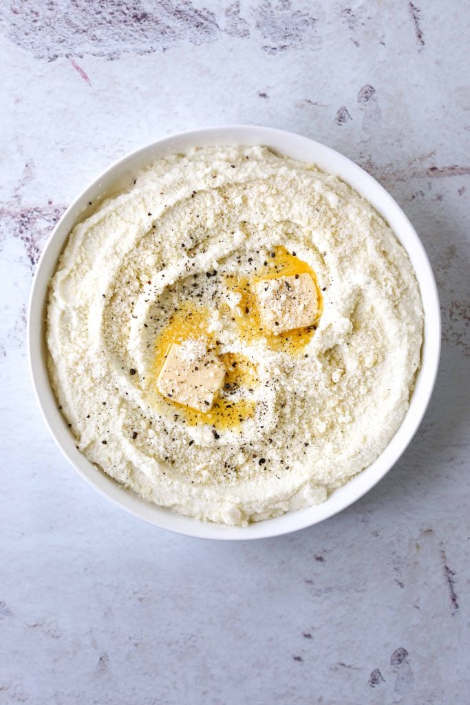 a white bowl filled with Cacio e Pepe Mashed Cauliflower