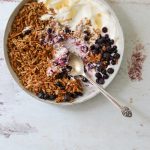 A bowl filled with yogurt, blueberries and coconut almond granola