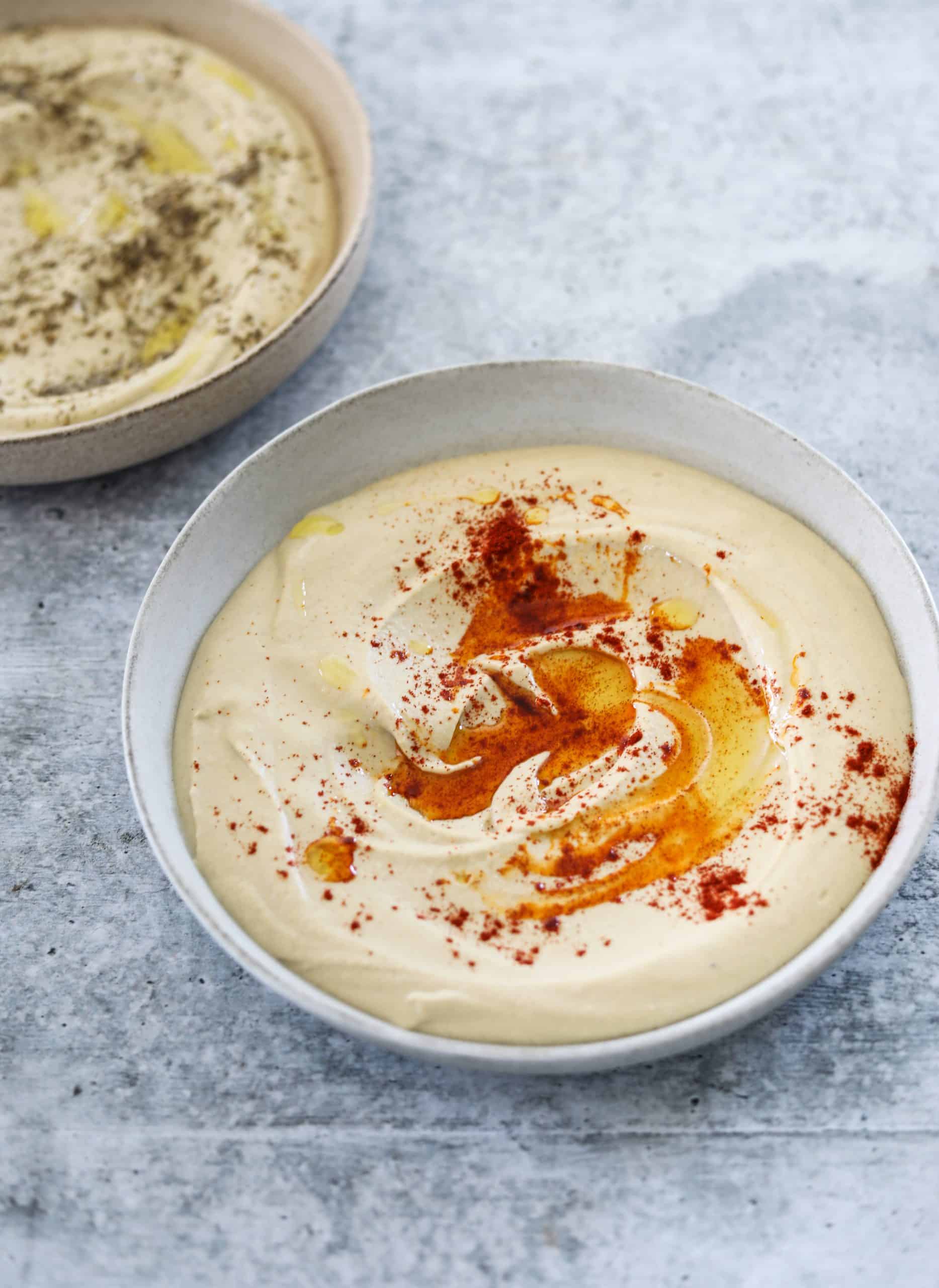 two bowls of Smooth and Creamy Homemade Hummus topped with olive oil and smoked paprika