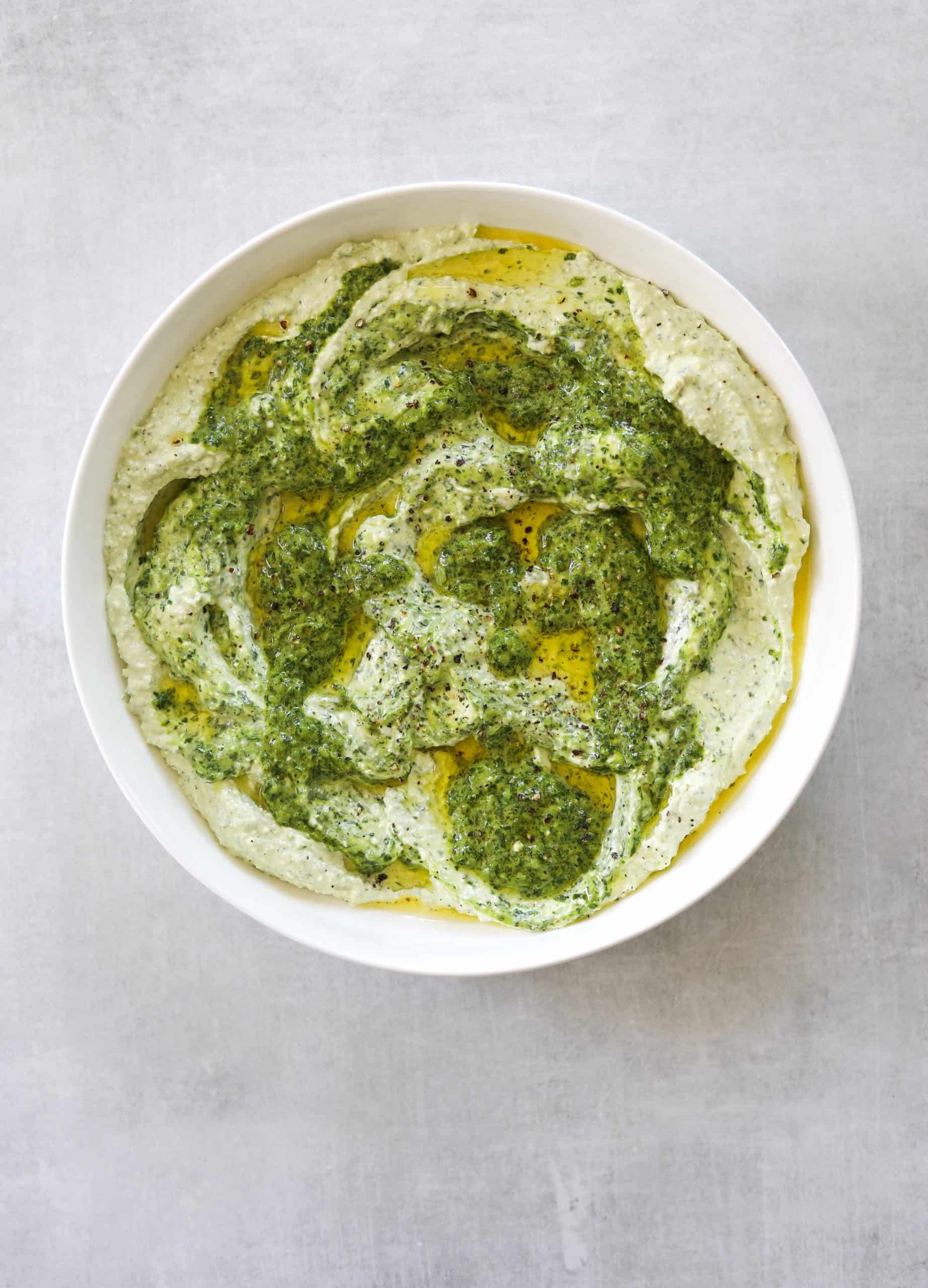 a white bowl filled with creamy whipped feta dip with jalapeño, garlic and fresh herbs