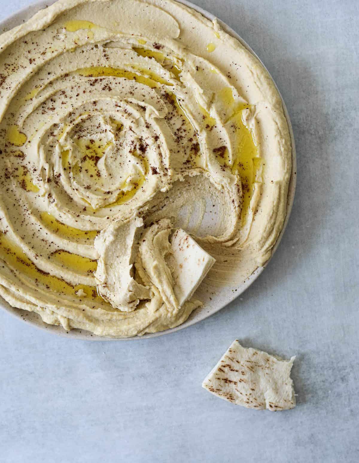 smooth and creamy hummus on a plate topped with olive oil and smoked paprika