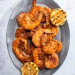an oval platter filled with grilled shrimp and grilled lemons