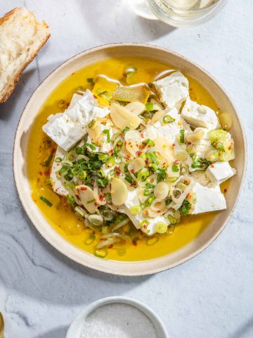A bowl of marinated feta cheese with olive oil, garlic, shallot and green onion