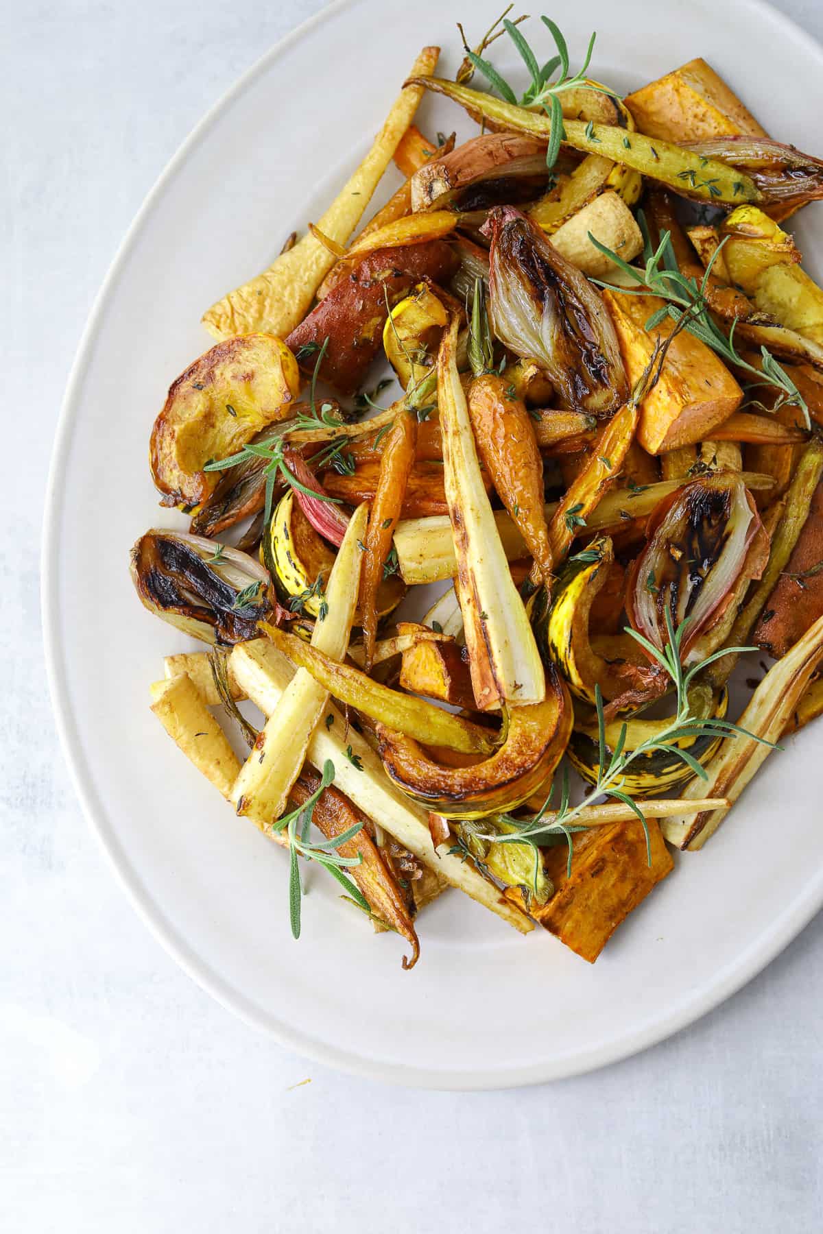 an oval platter filled with roasted root vegetables; carrots, parsnips, shallot, rosemary and thyme 