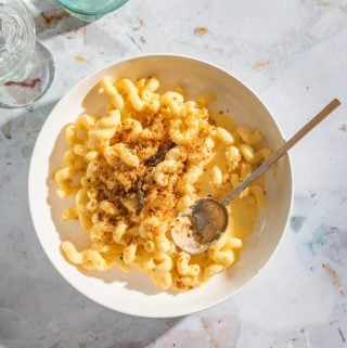 a white bowl of butternut squash macaroni and cheese topped with breadcrumb with a gold spoon