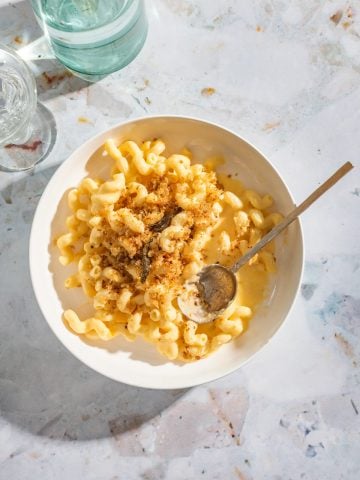 a white bowl of butternut squash macaroni and cheese topped with breadcrumb with a gold spoon