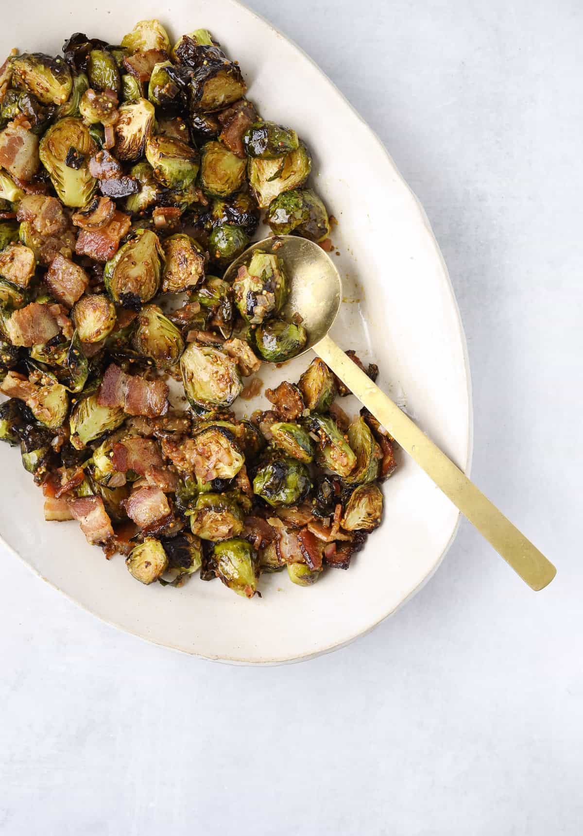 roasted Brussels sprouts with bacon and whole grain mustard and a gold spoon 