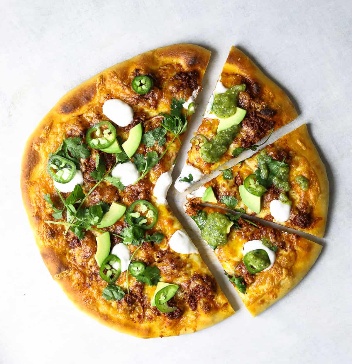 a Chorizo and Avocado Pizza cut into slices and topped with sour cream and salsa