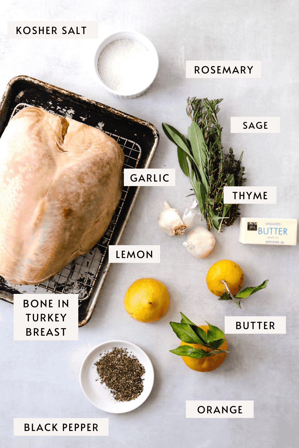 recipe ingredients, a large raw turkey breast on a baking tray, orange, fresh sage, thyme and rosemary, black pepper 