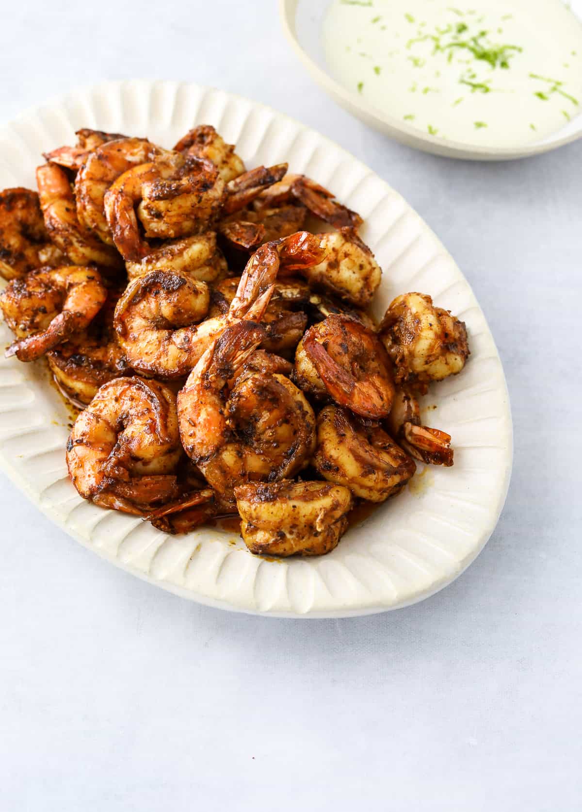 an oval platter of blackened shrimp and a bowl of garlic-lime aioli