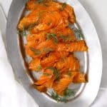 a silver plate of thinly sliced citrus cured salmon topped with fresh dil