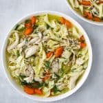 a large white bowl filled with Rotisserie Chicken Noodle Soup, fresh herb and egg noodles